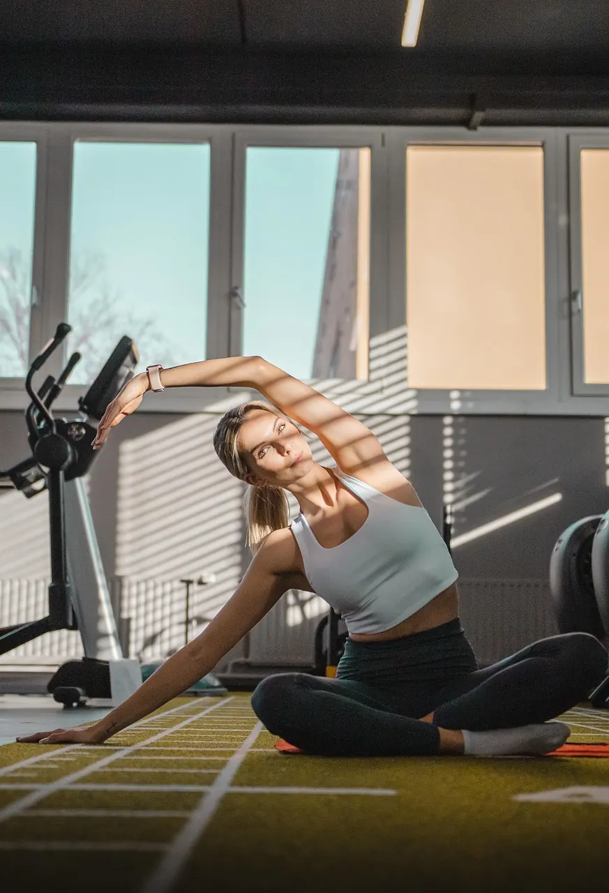 An athlete working through a deep side stretch on the gym floor