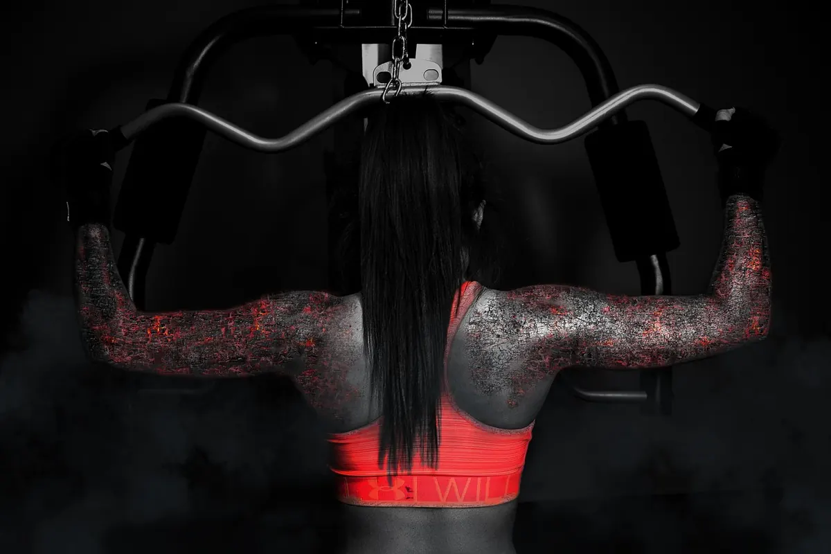 An athlete under a loaded barbell, seen from behind in a dark gym
